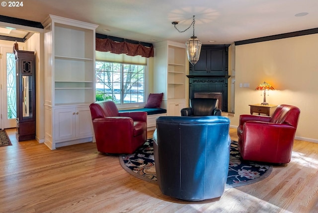 living room with ornamental molding, light wood-type flooring, a fireplace, and built in features