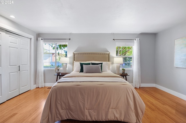 bedroom featuring multiple windows, a closet, and light hardwood / wood-style floors