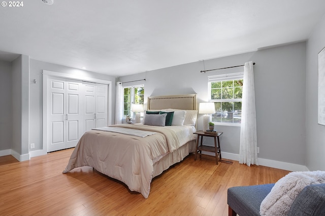 bedroom with a closet, light hardwood / wood-style floors, and multiple windows