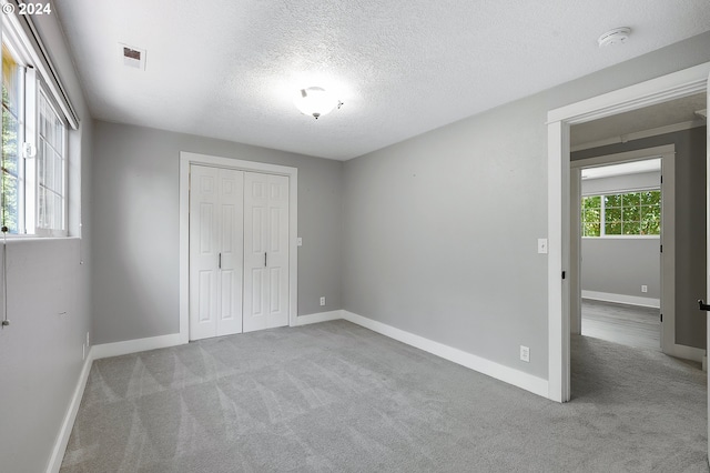 unfurnished bedroom featuring a closet, light colored carpet, and a textured ceiling