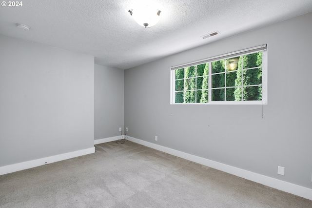 empty room with light carpet and a textured ceiling