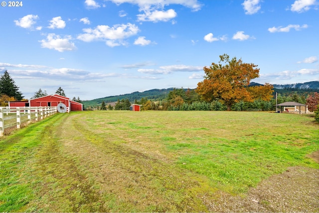 view of yard with a mountain view, a rural view, and an outbuilding