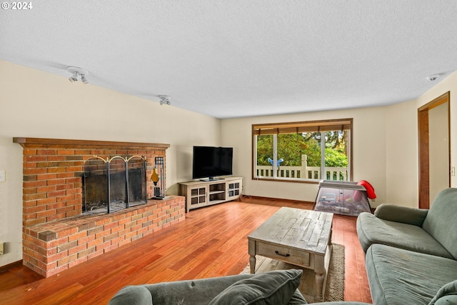 living room with a fireplace, a textured ceiling, and wood finished floors