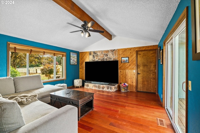 living room featuring wooden walls, vaulted ceiling with beams, ceiling fan, a textured ceiling, and wood-type flooring