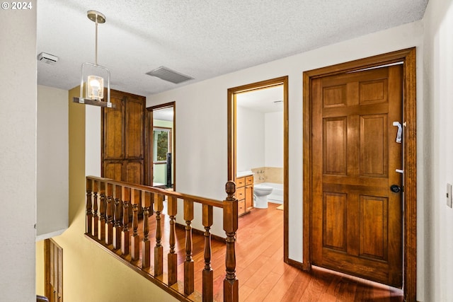 corridor with a textured ceiling and hardwood / wood-style flooring