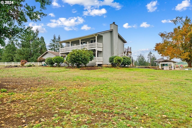 rear view of house with a lawn and a balcony