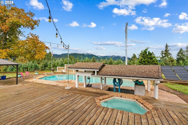 view of swimming pool featuring an in ground hot tub and a deck with mountain view