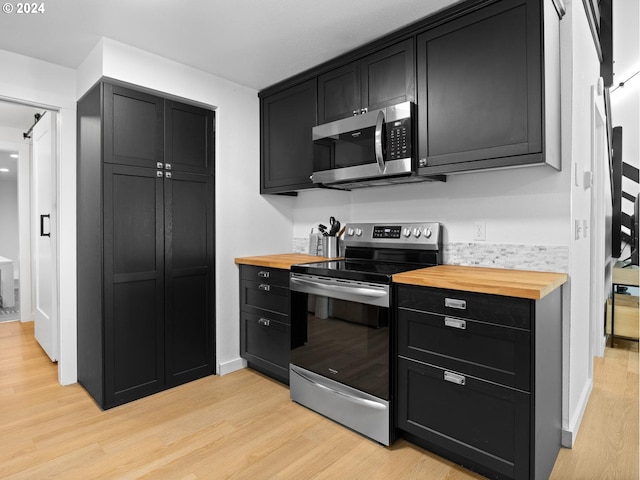 kitchen featuring butcher block countertops, light hardwood / wood-style flooring, and appliances with stainless steel finishes