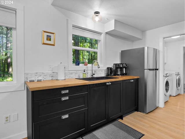 kitchen featuring a healthy amount of sunlight, sink, washer and dryer, and light wood-type flooring