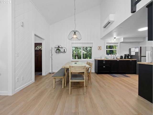 dining room featuring light wood-type flooring, sink, high vaulted ceiling, and a wall mounted AC