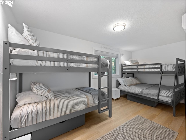 bedroom with light wood-type flooring and a textured ceiling