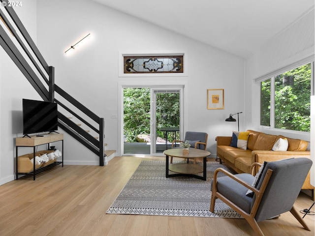 living room with light hardwood / wood-style floors and high vaulted ceiling