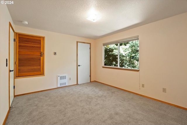 carpeted empty room featuring heating unit and a textured ceiling