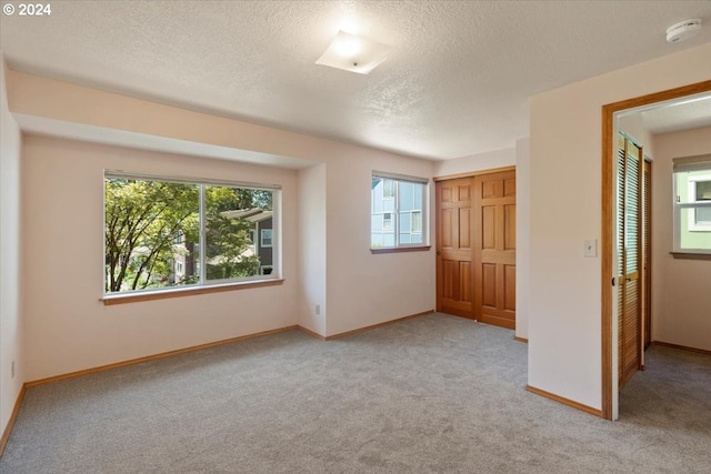 unfurnished bedroom with light colored carpet, a closet, and a textured ceiling