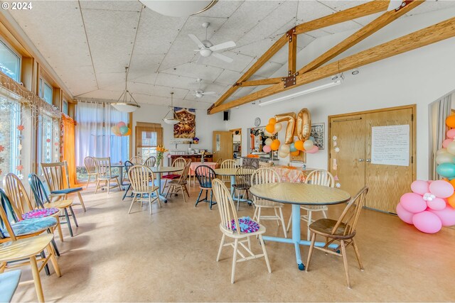 dining room with high vaulted ceiling, concrete floors, and ceiling fan