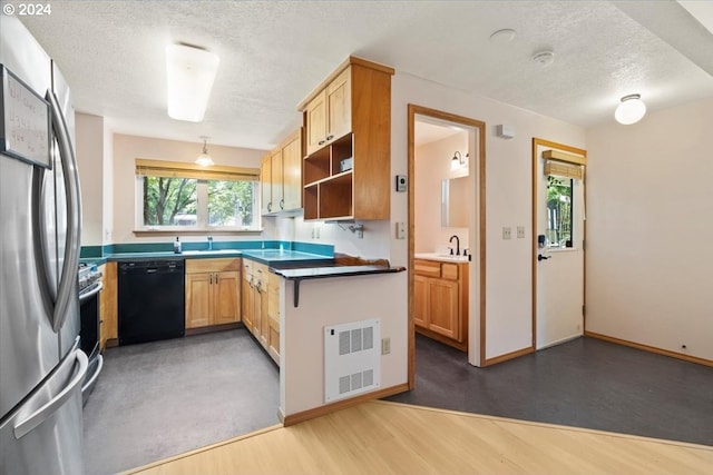 kitchen with dark wood-type flooring, appliances with stainless steel finishes, light brown cabinetry, and a textured ceiling