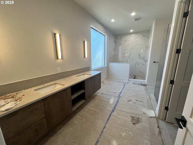 bathroom with tiled shower and vanity