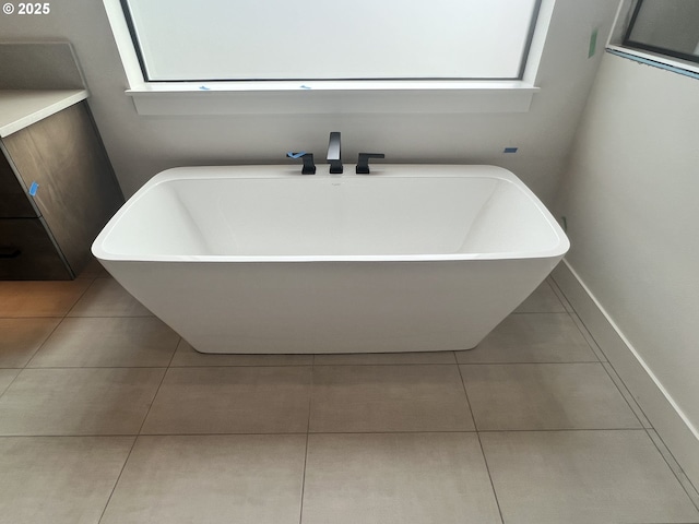 bathroom with tile patterned flooring, a tub to relax in, and a healthy amount of sunlight