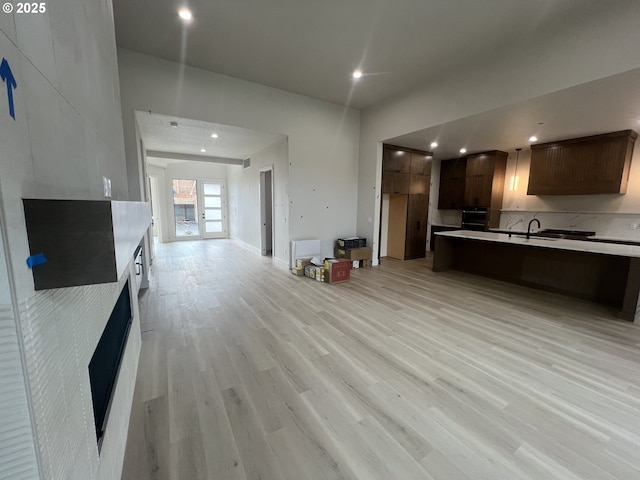 kitchen with dark brown cabinetry, sink, light hardwood / wood-style floors, and oven