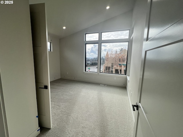 spare room featuring light carpet, a wealth of natural light, and vaulted ceiling