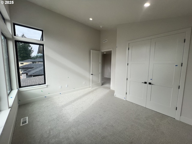 unfurnished bedroom featuring light colored carpet, high vaulted ceiling, and a closet