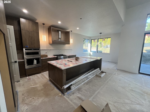 kitchen featuring hanging light fixtures, stainless steel appliances, a textured ceiling, a center island, and dark brown cabinetry