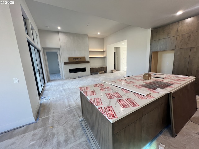 kitchen featuring dark brown cabinetry, a center island, and a fireplace