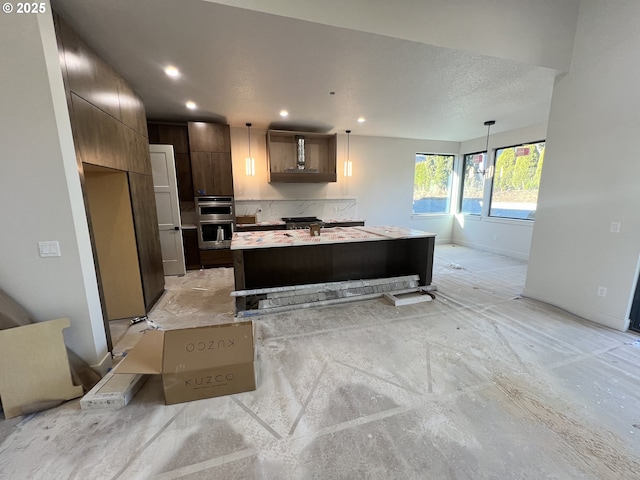 kitchen featuring hanging light fixtures, dark brown cabinetry, stainless steel double oven, and a kitchen island