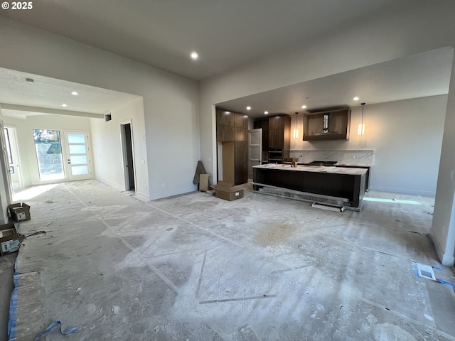 kitchen with dark brown cabinetry, a center island, decorative backsplash, and a breakfast bar