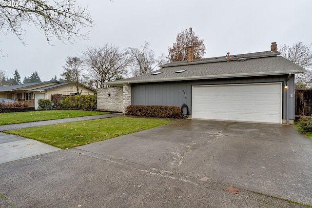 view of front of property with a shingled roof, concrete driveway, an attached garage, and a front lawn