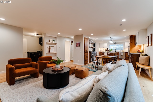 living room featuring recessed lighting, baseboards, and light wood finished floors