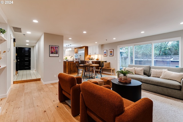 living room with recessed lighting, visible vents, baseboards, and light wood-style floors