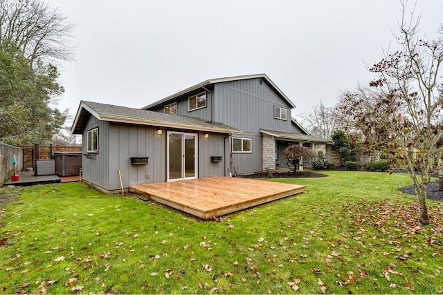 rear view of property with a yard, a deck, a jacuzzi, and fence