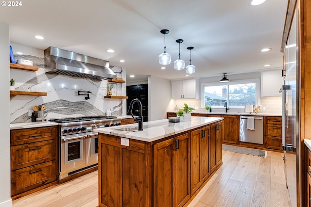 kitchen featuring light wood-style flooring, open shelves, a sink, stainless steel appliances, and wall chimney exhaust hood