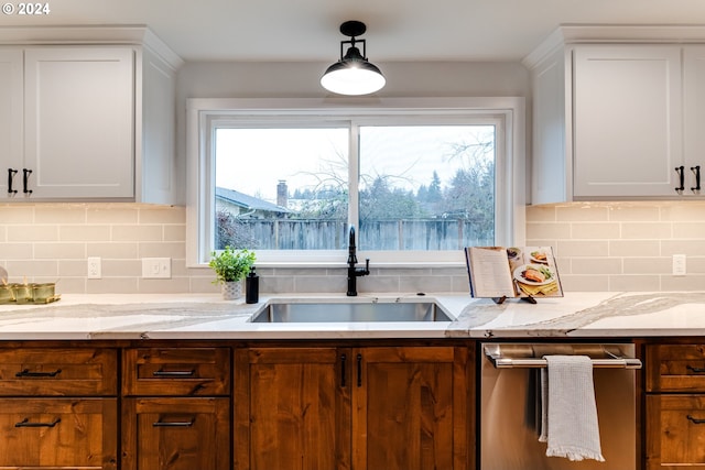 kitchen with white cabinets, light stone countertops, and a sink