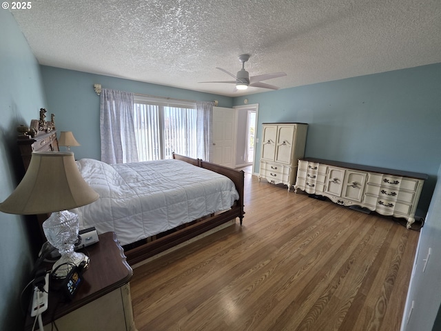 bedroom with ceiling fan, a textured ceiling, and wood finished floors