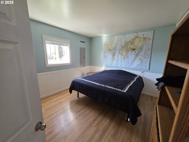 bedroom featuring a wainscoted wall and wood finished floors