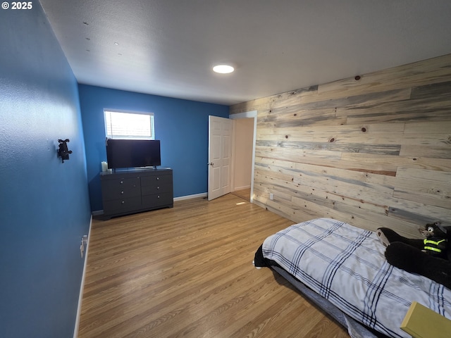 bedroom featuring wood walls, baseboards, and wood finished floors