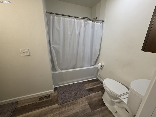 bathroom featuring visible vents, toilet, shower / bath combo, wood finished floors, and baseboards