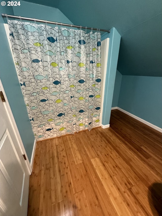 bathroom featuring lofted ceiling, hardwood / wood-style flooring, and a shower with curtain