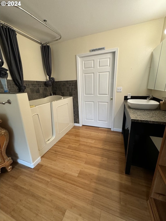 bathroom with a tub, vanity, and hardwood / wood-style floors