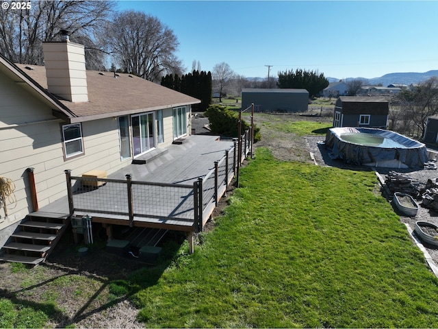 view of yard featuring a deck with mountain view and an outbuilding