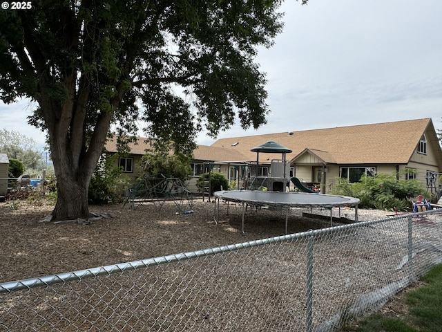 rear view of property with playground community and fence