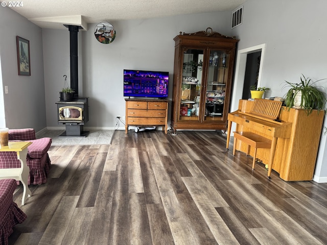 living room with a textured ceiling, hardwood / wood-style floors, and a wood stove