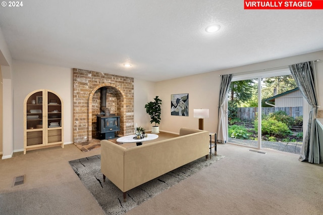 living area featuring a wood stove, baseboards, visible vents, and light colored carpet