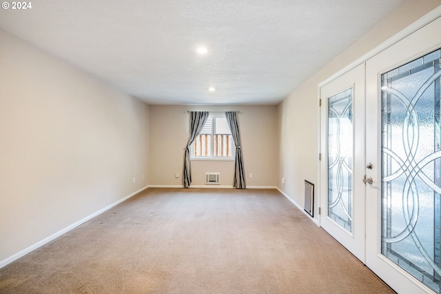 spare room with light colored carpet and french doors