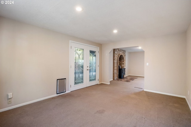 unfurnished living room with carpet floors, a wood stove, and french doors