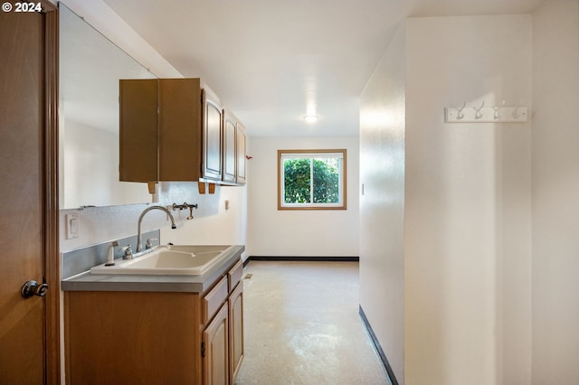 kitchen featuring baseboards, brown cabinets, light countertops, concrete floors, and a sink