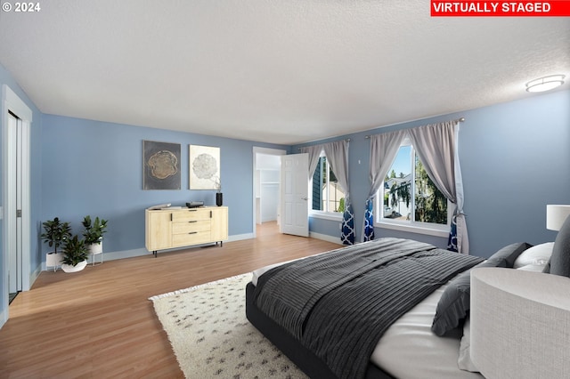 bedroom with light wood-style floors, baseboards, and a textured ceiling