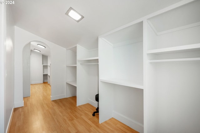 spacious closet featuring light wood-type flooring and arched walkways